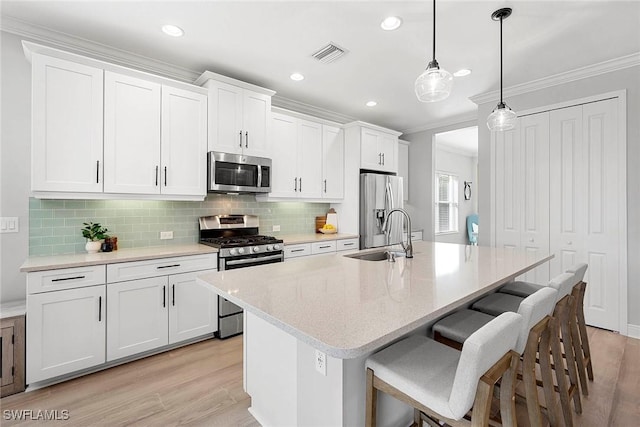 kitchen with appliances with stainless steel finishes, pendant lighting, white cabinetry, and a sink