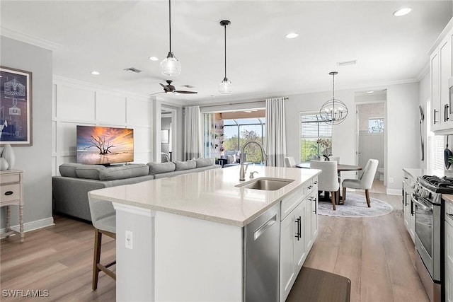 kitchen featuring appliances with stainless steel finishes, open floor plan, white cabinets, and a sink