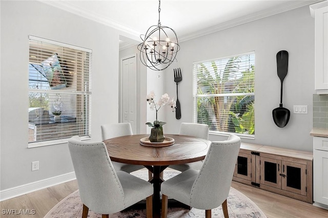 dining room featuring an inviting chandelier, light wood-style flooring, baseboards, and crown molding