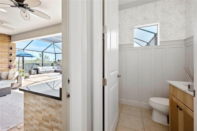 bathroom with a decorative wall, a ceiling fan, vanity, tile patterned flooring, and wallpapered walls