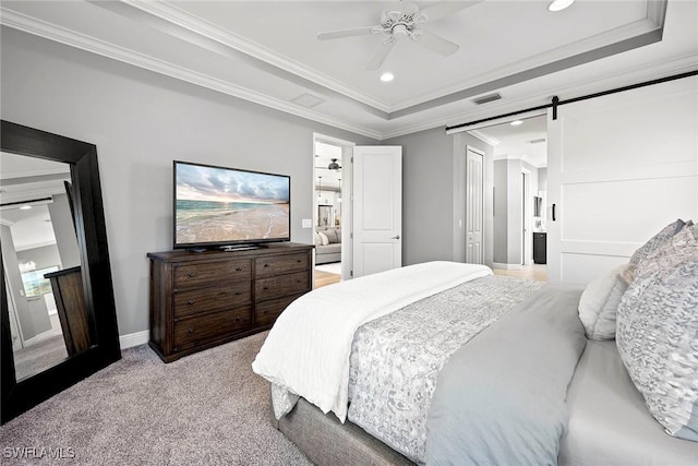 bedroom with light carpet, a barn door, visible vents, and a tray ceiling