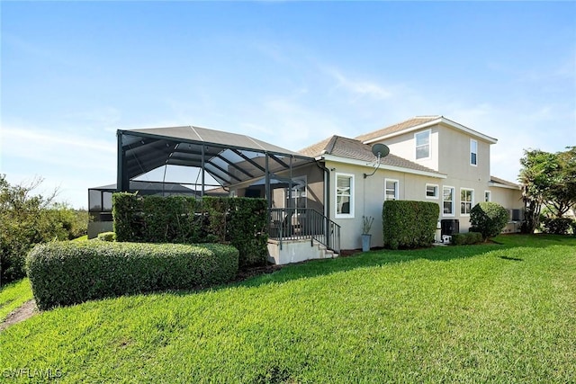 back of house featuring glass enclosure, a yard, and stucco siding