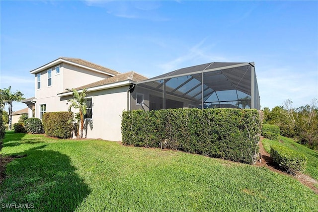 view of home's exterior with glass enclosure, a lawn, and stucco siding