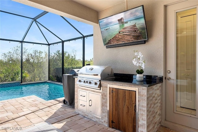 outdoor pool with a patio, glass enclosure, an outdoor kitchen, and a grill