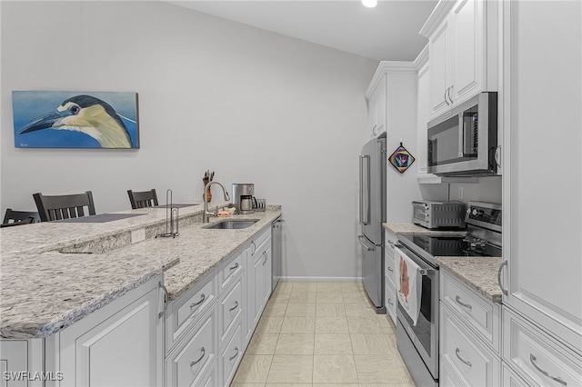 7629 Captains Harbor Dr Unit 1203, Bokeelia, FL 33922 - kitchen featuring a sink, white cabinetry, a kitchen breakfast bar, appliances with stainless steel finishes, and light stone countertops