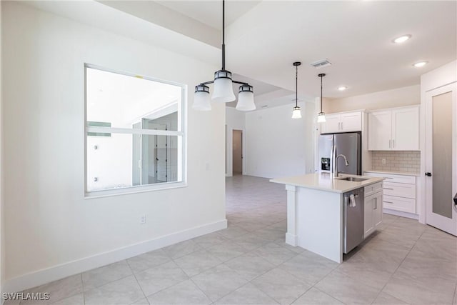 kitchen featuring pendant lighting, stainless steel appliances, light countertops, a kitchen island with sink, and white cabinetry