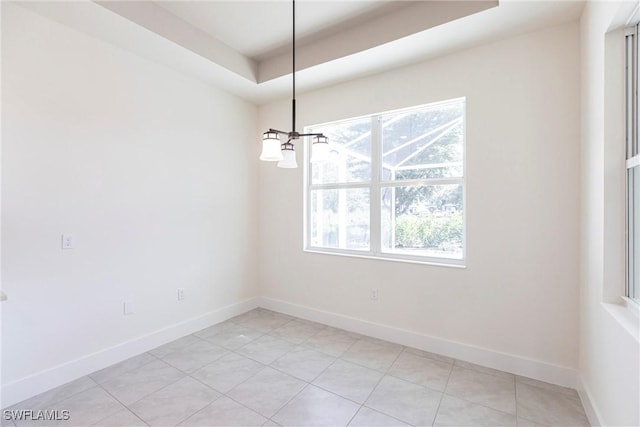 unfurnished room featuring plenty of natural light, baseboards, and a notable chandelier