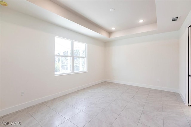 spare room featuring a tray ceiling, visible vents, baseboards, and recessed lighting