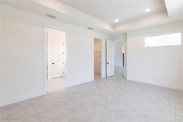 empty room with baseboards, visible vents, a tray ceiling, and recessed lighting