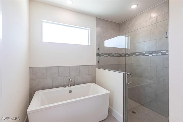 bathroom with a shower stall, tile walls, a freestanding bath, and recessed lighting