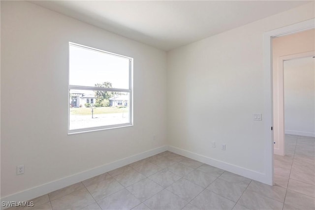 empty room with light tile patterned floors and baseboards