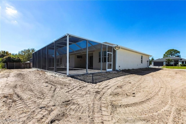 back of property with a lanai, fence, and stucco siding