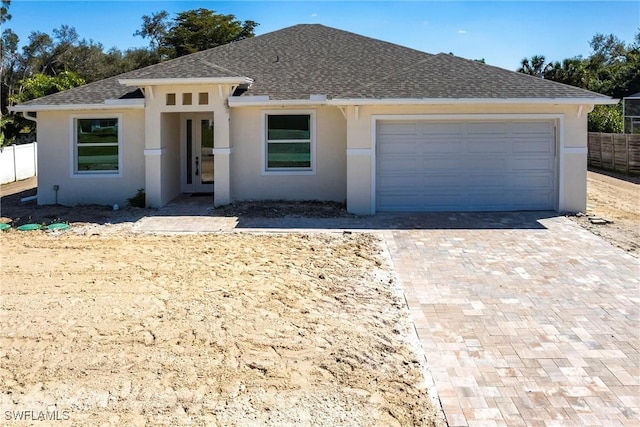 view of front of home featuring a garage, fence, decorative driveway, and stucco siding