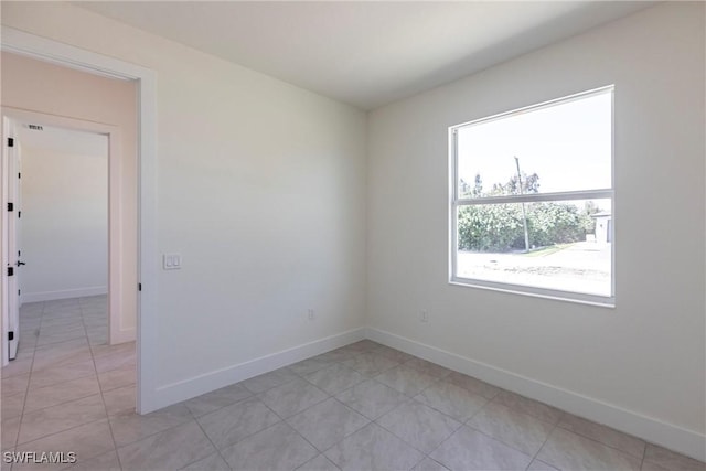 spare room with light tile patterned floors and baseboards