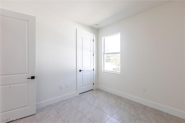 unfurnished room featuring baseboards and light tile patterned floors