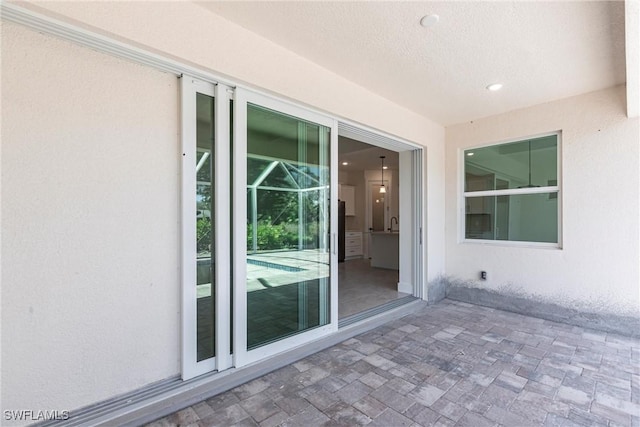 entrance to property featuring a patio and stucco siding