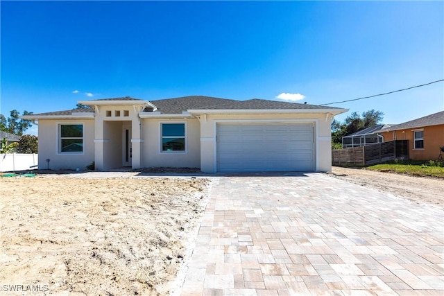 view of front facade featuring a garage, decorative driveway, fence, and stucco siding