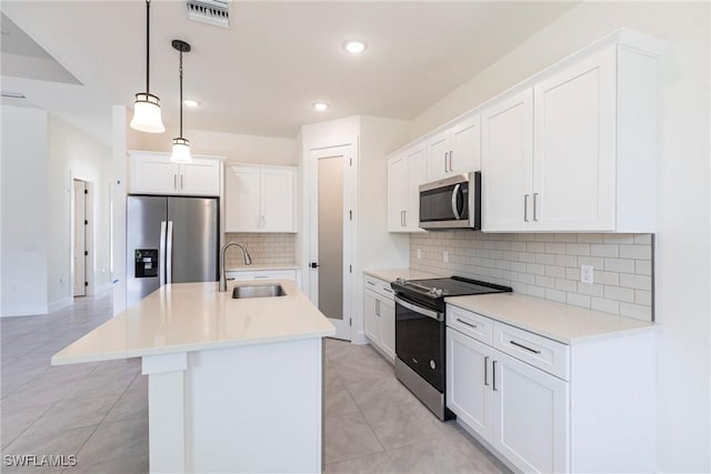 kitchen featuring white cabinets, appliances with stainless steel finishes, light countertops, pendant lighting, and a sink