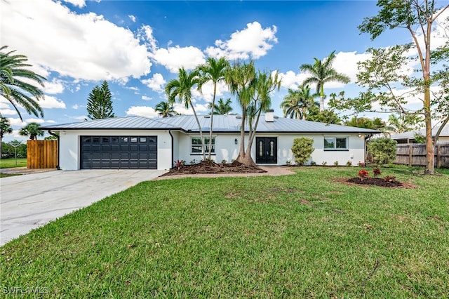 ranch-style house with metal roof, concrete driveway, an attached garage, and fence