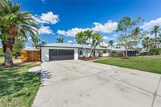 ranch-style house featuring an attached garage, fence, driveway, stucco siding, and a front yard