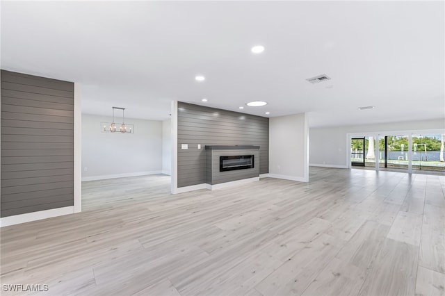 unfurnished living room with light wood-style floors, baseboards, a fireplace, and visible vents