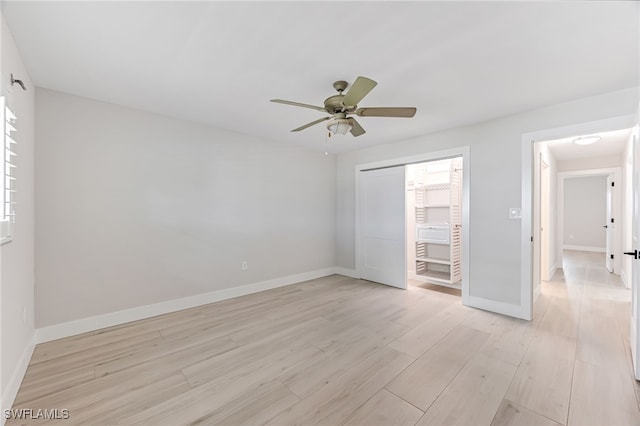 unfurnished bedroom with a closet, light wood-style floors, a ceiling fan, multiple windows, and baseboards