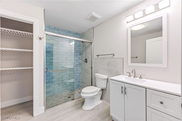 full bath with a walk in closet, visible vents, toilet, a stall shower, and vanity