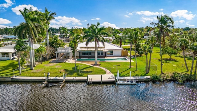 rear view of house featuring a patio area, an outdoor pool, a water view, and a yard