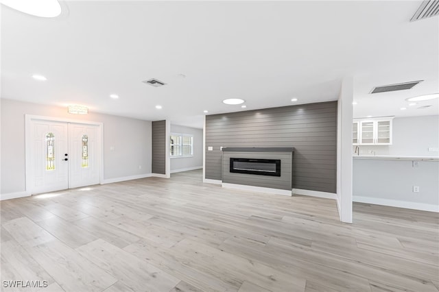 unfurnished living room with light wood-type flooring, a fireplace, and visible vents