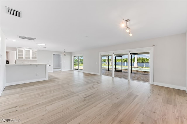 unfurnished living room with light wood-type flooring, baseboards, and visible vents