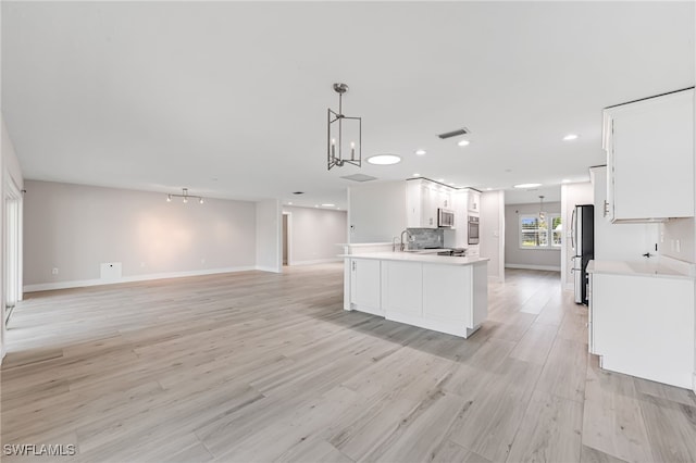 kitchen featuring stainless steel appliances, white cabinets, open floor plan, light countertops, and light wood finished floors