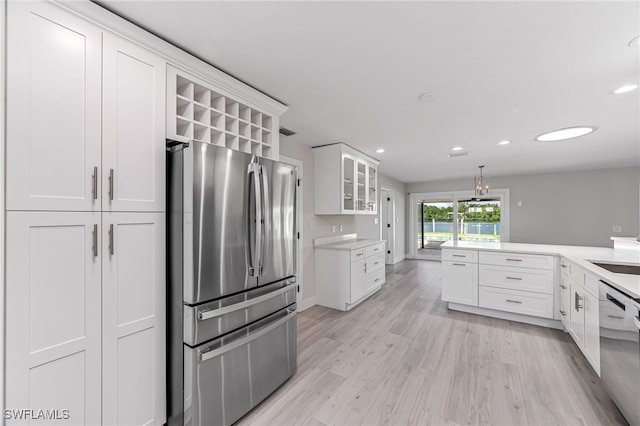 kitchen featuring light countertops, appliances with stainless steel finishes, light wood-style floors, glass insert cabinets, and white cabinetry