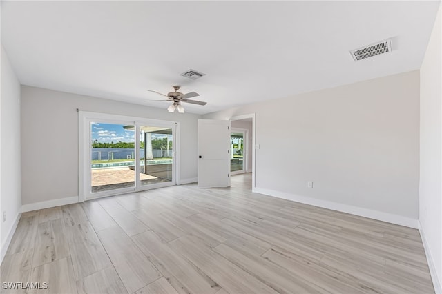 unfurnished room with light wood-style floors, baseboards, visible vents, and ceiling fan