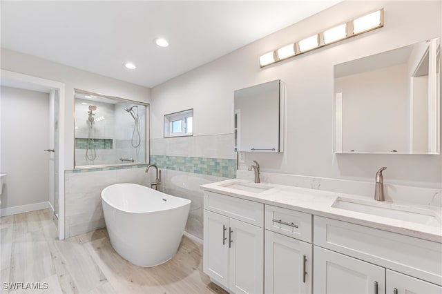 full bathroom with double vanity, a shower stall, a freestanding bath, and a sink