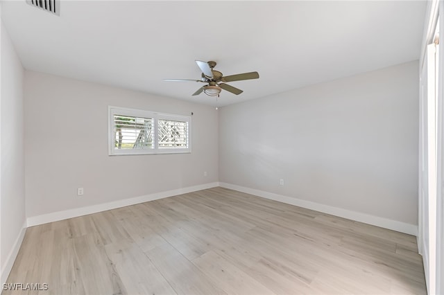 spare room featuring light wood-type flooring, visible vents, and baseboards