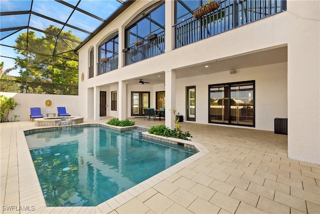 view of pool with french doors, a pool with connected hot tub, a ceiling fan, glass enclosure, and a patio area