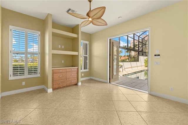 unfurnished room featuring light tile patterned floors, baseboards, visible vents, and a ceiling fan