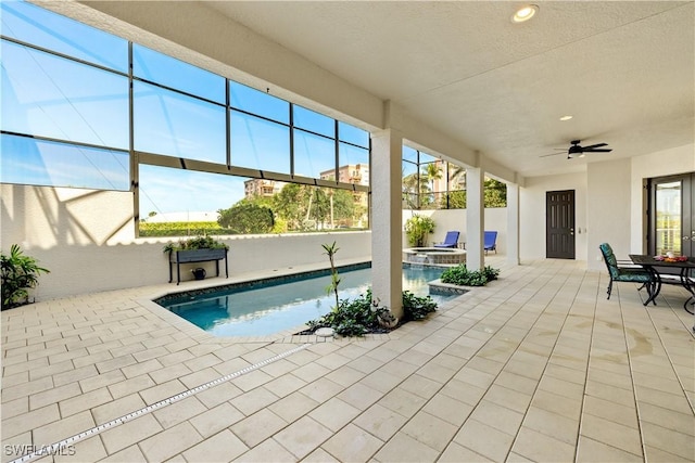 view of swimming pool featuring a patio, glass enclosure, a pool with connected hot tub, and a ceiling fan