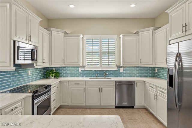 kitchen featuring appliances with stainless steel finishes, white cabinets, and a sink