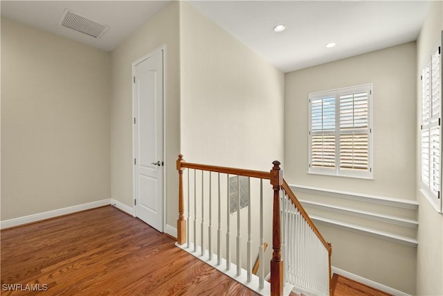 hall with recessed lighting, visible vents, an upstairs landing, wood finished floors, and baseboards