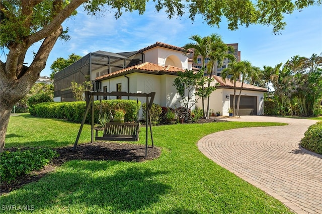 mediterranean / spanish home with a tiled roof, decorative driveway, a front yard, and stucco siding