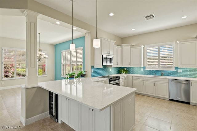 kitchen with beverage cooler, visible vents, a peninsula, stainless steel appliances, and a sink