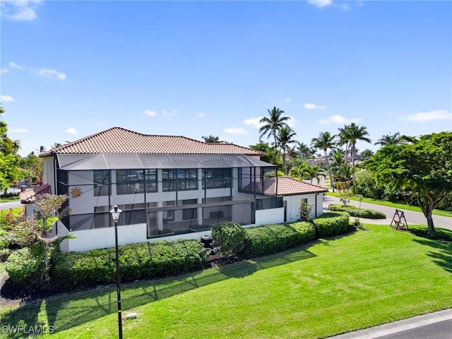 back of property with a lanai, a yard, and a tiled roof