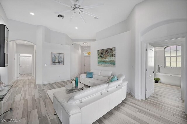 living area featuring visible vents, arched walkways, baseboards, light wood-style flooring, and recessed lighting