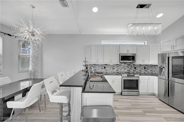 kitchen featuring stainless steel appliances, dark stone countertops, a sink, and pendant lighting