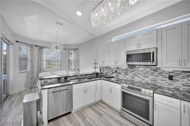 kitchen featuring a chandelier, appliances with stainless steel finishes, hanging light fixtures, white cabinetry, and a sink