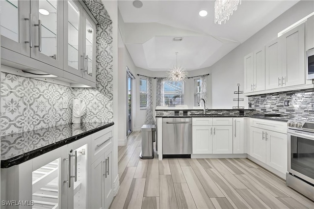 kitchen featuring appliances with stainless steel finishes, dark countertops, and a notable chandelier