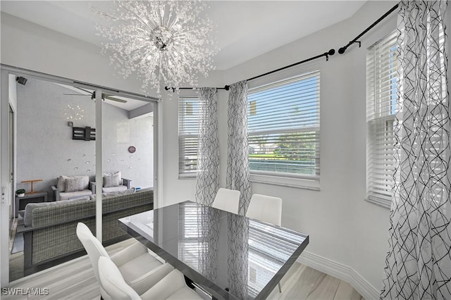 dining space with a chandelier, light wood finished floors, and baseboards