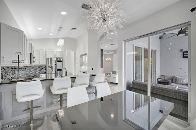 kitchen with arched walkways, white cabinets, dark countertops, appliances with stainless steel finishes, and decorative light fixtures