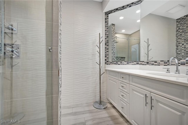 full bathroom with a stall shower, tile walls, and vanity